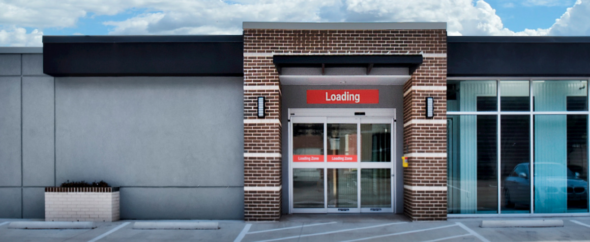 Exterior view of the facility's dedicated "Loading" zone featuring sliding glass doors and a brick entryway.