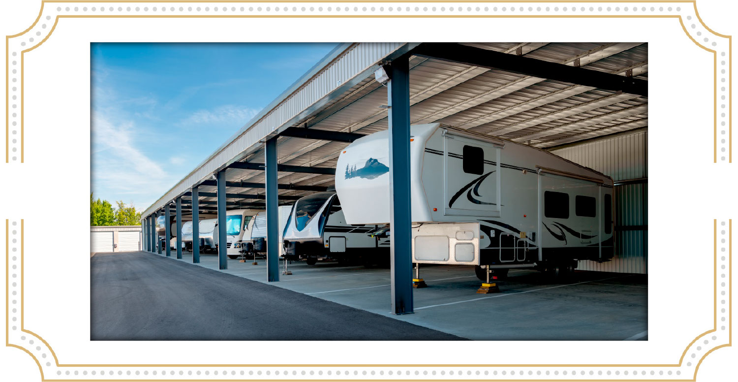 Multiple white and black recreational vehicles parked under a long metal storage canopy at a professional facility.