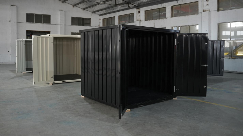 Interior view of a warehouse showing several open-door metal storage containers in black and beige. The units have corrugated walls and are displayed on a concrete floor under high ceilings.