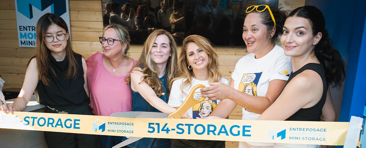 A joyful grand opening event featuring Margaux Chetrit and her team smiling as they cut a ceremonial yellow ribbon labeled "514-STORAGE" inside a wood-paneled facility office
