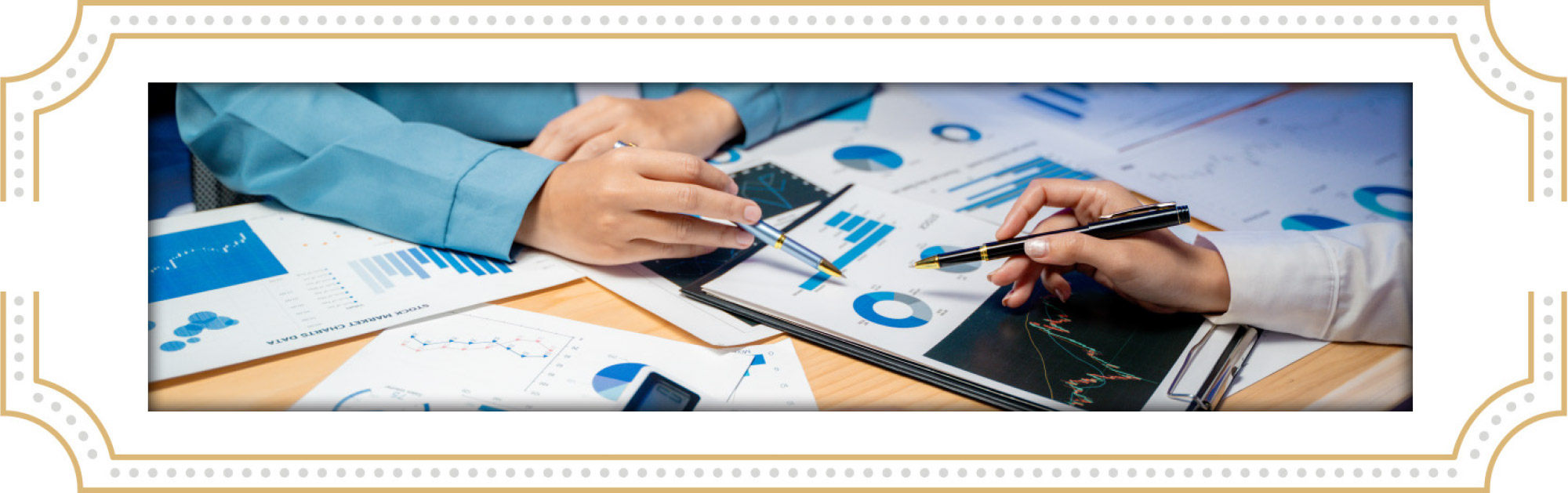 two people at table pointing with pens to papers on desk