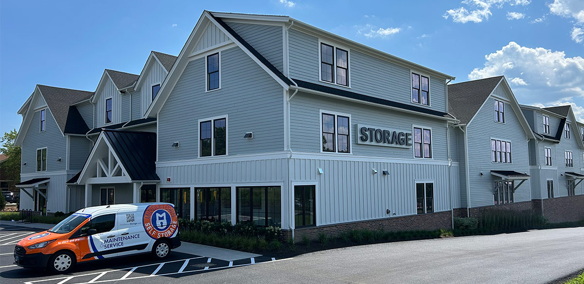 Exterior of a large, multi-story "Middletown Self Storage" facility with light blue siding and a maintenance service van parked in front.
