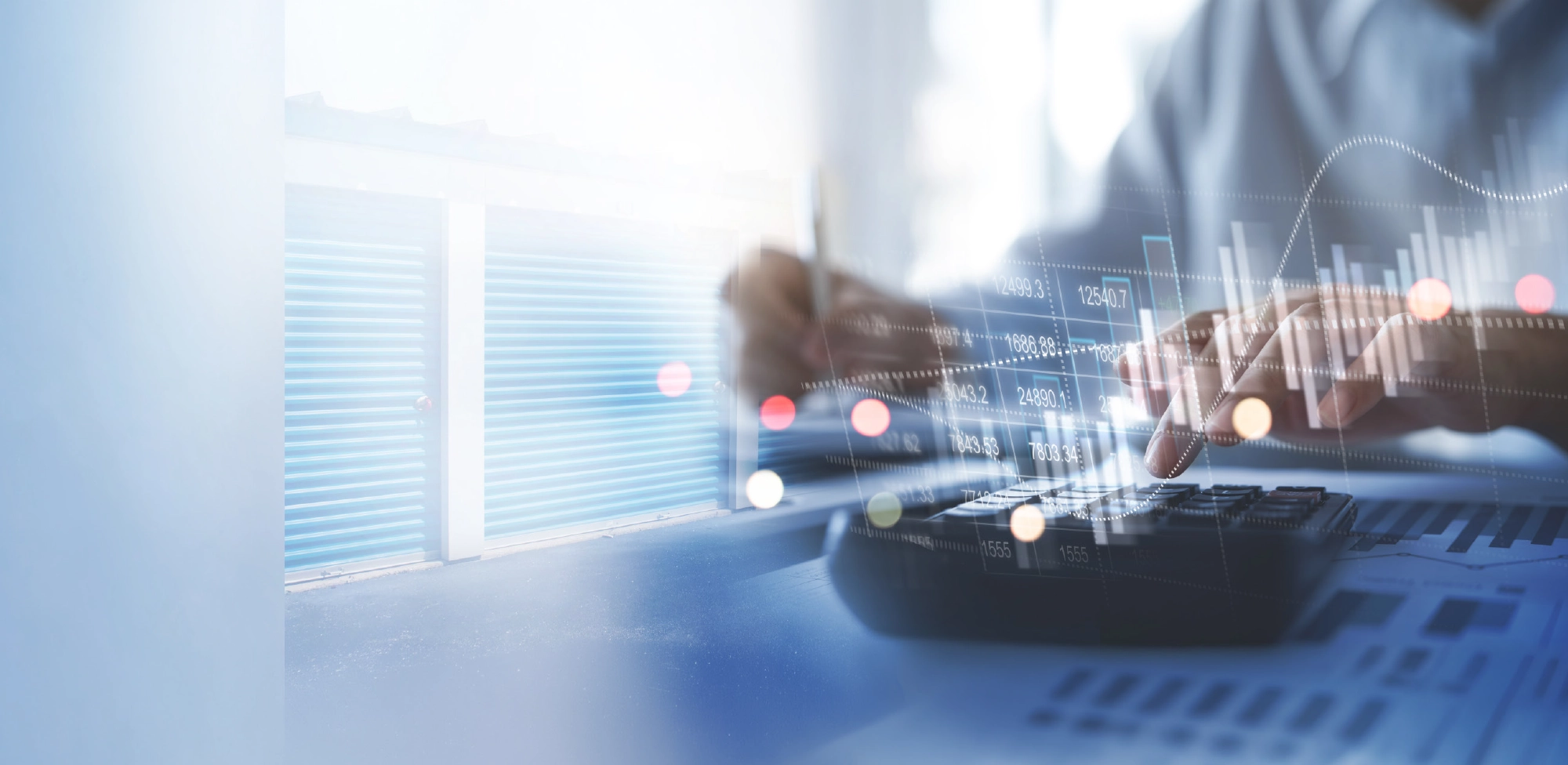 A double-exposure image showing a person using a calculator and reviewing financial documents, overlaid with a glowing digital bar graph and a background image of blue self-storage unit doors