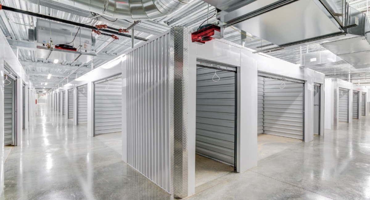 Clean interior hallway of a climate-controlled storage facility with white corrugated metal unit doors.