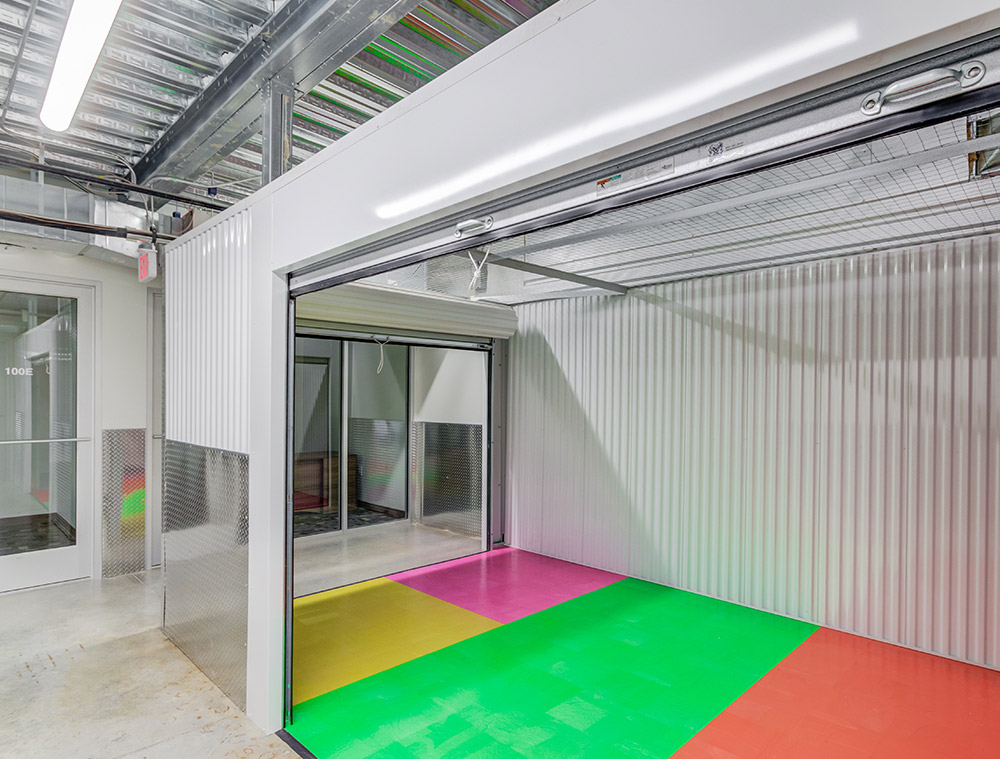 Interior view of an open storage unit featuring a vibrant, multi-colored floor with pink, yellow, green, and red tiles.