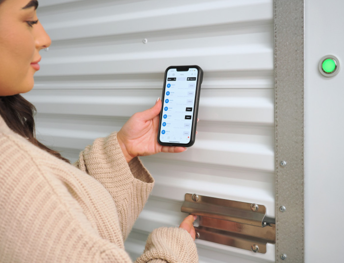 woman holding phone up to storage unit door