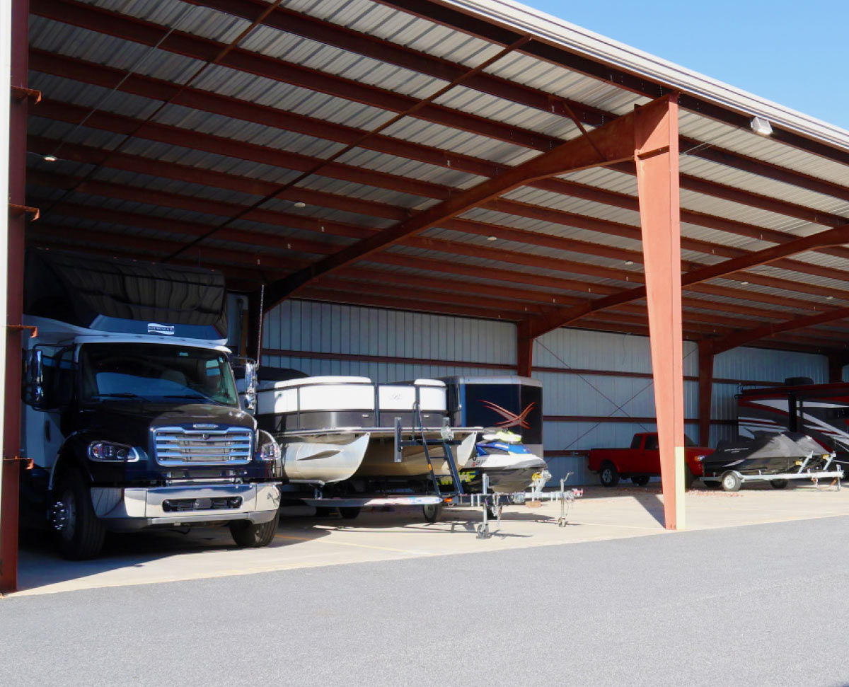 Large covered vehicle storage area at StoreEase housing a semi-truck, pontoon boat, jet ski, and trailer.