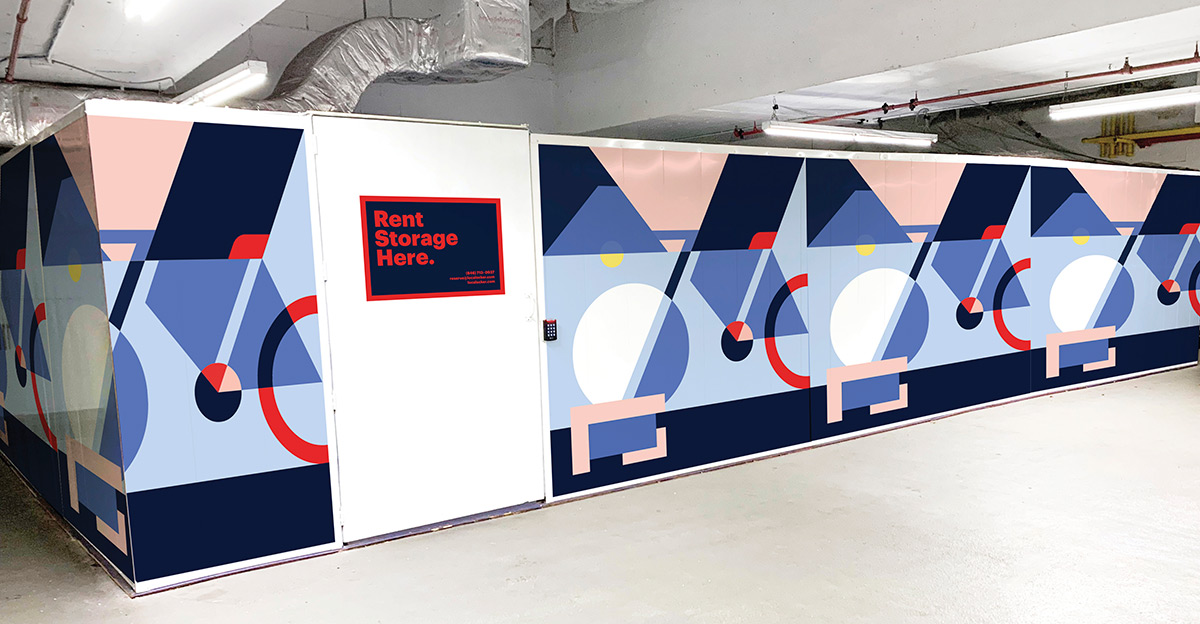 Enclosed storage structure on Riverside Boulevard with a geometric bicycle mural on the walls and a white door displaying a red "Rent Storage Here" sign.