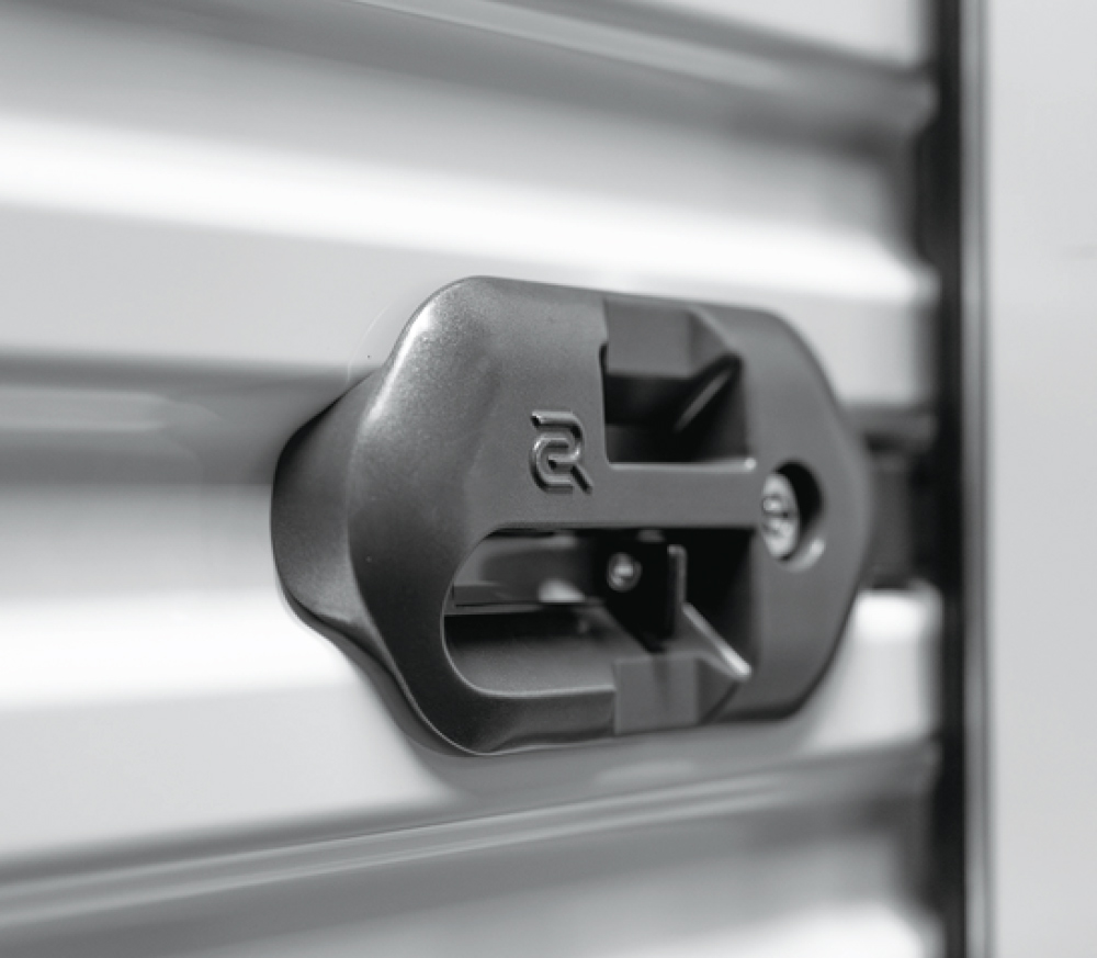 A close-up, selective-focus shot of a modern, heavy-duty grey sliding lock on a corrugated white storage door.