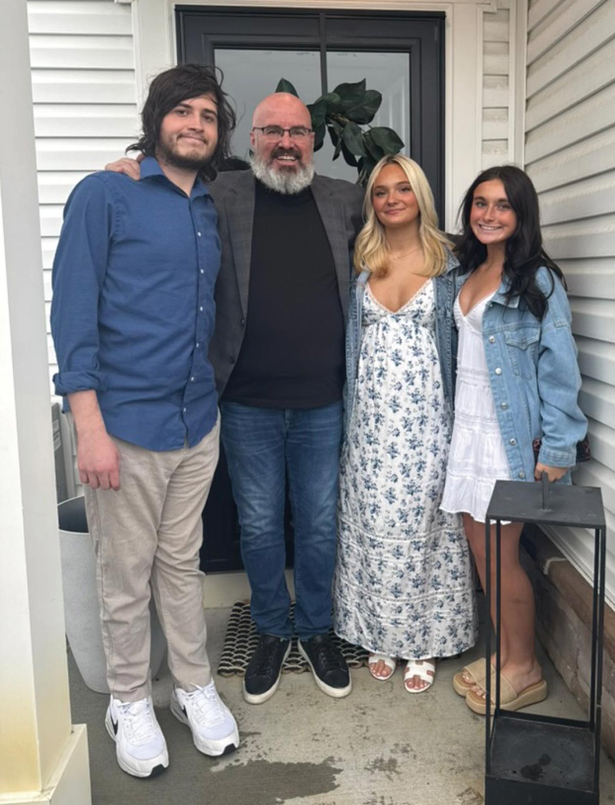 Thaddeus Campbell and his children standing together on a concrete front porch of a home