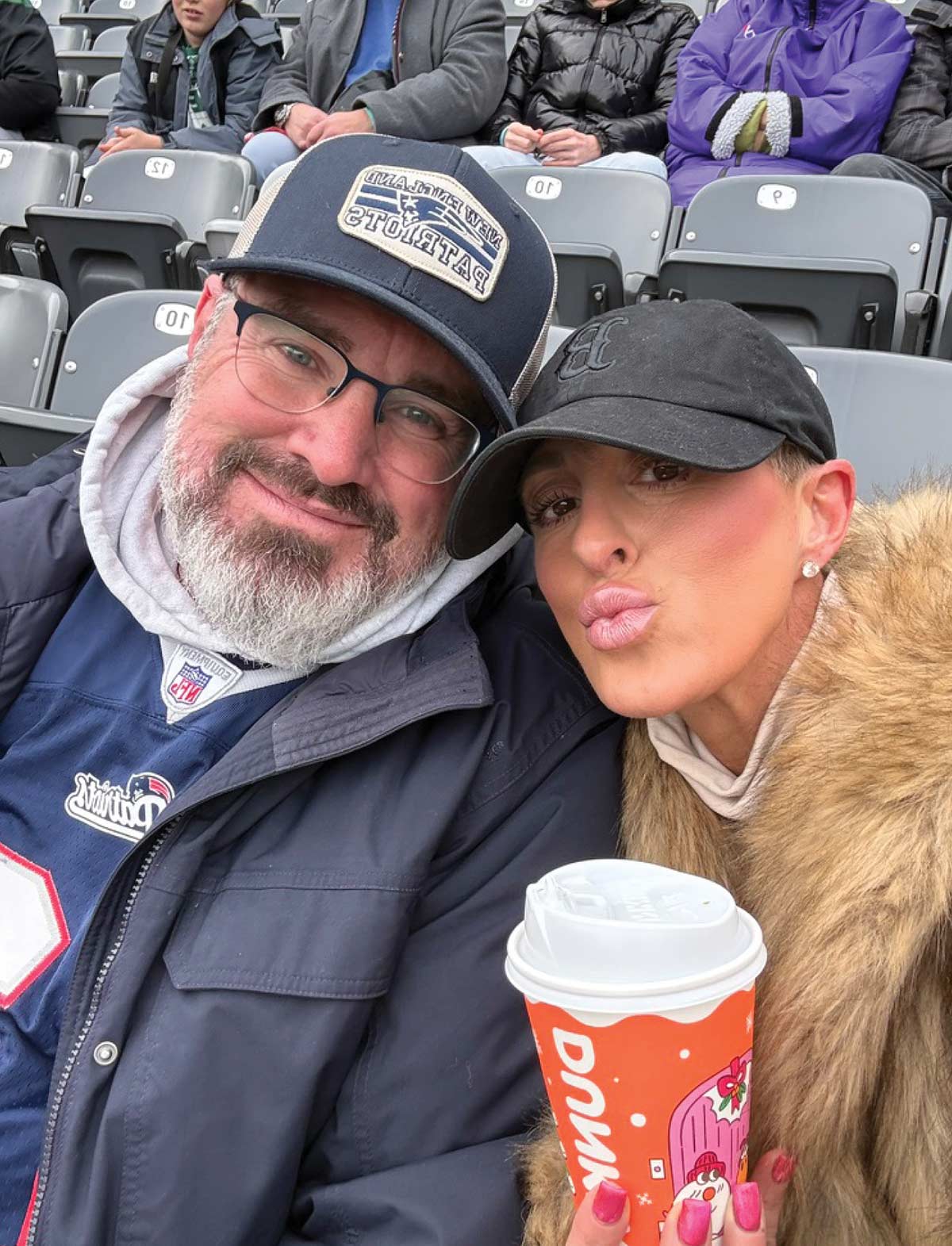 Selfie of Thaddeus Campbell and his wife sitting in stadium seats at an outdoor sporting event