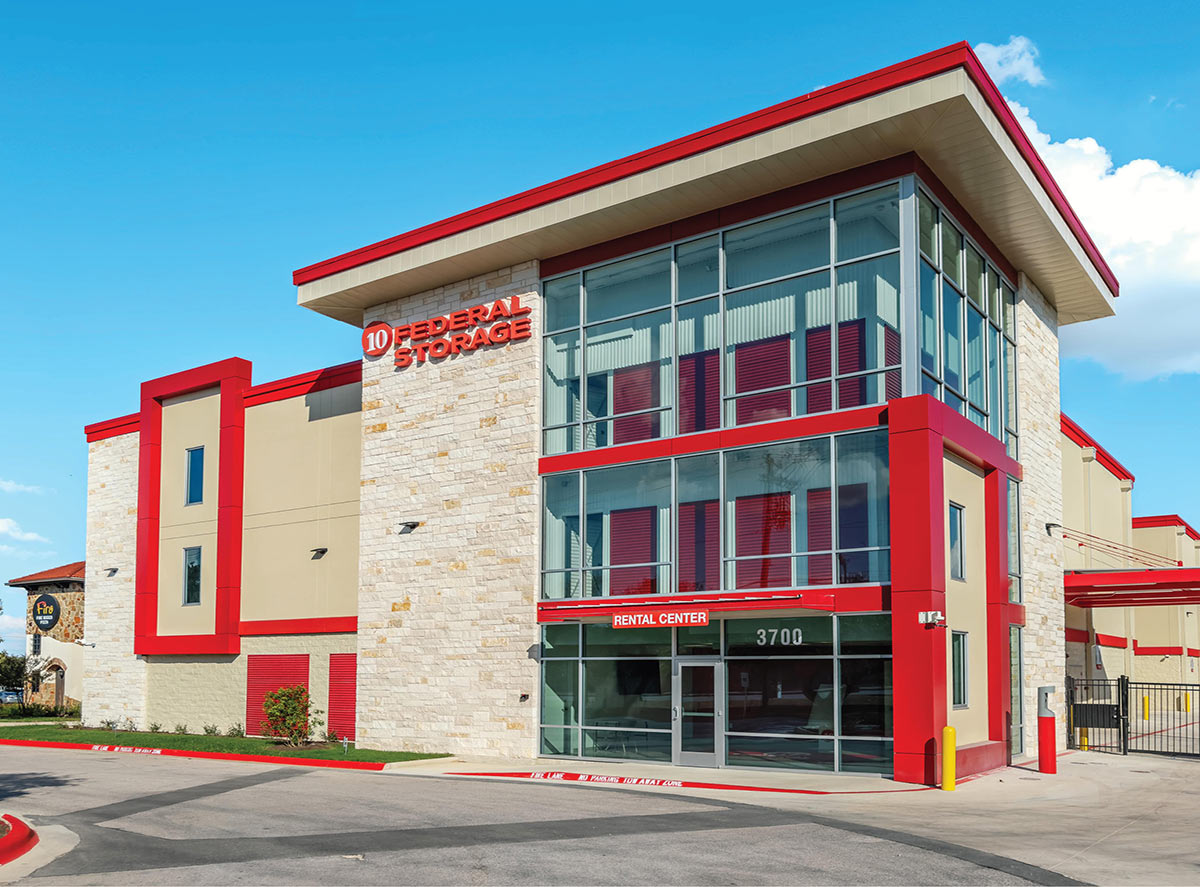 Exterior view of a 10 Federal Storage Facility nearby an asphalt driveway which passes in front under a clear blue sky