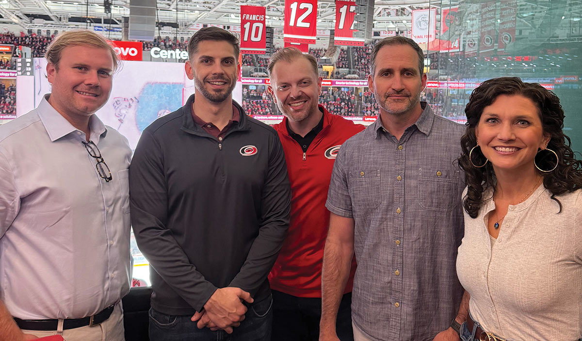 10 Federal Storage team members smiling and posing together in an indoor stadium luxury suite during a Carolina Hurricanes hockey game