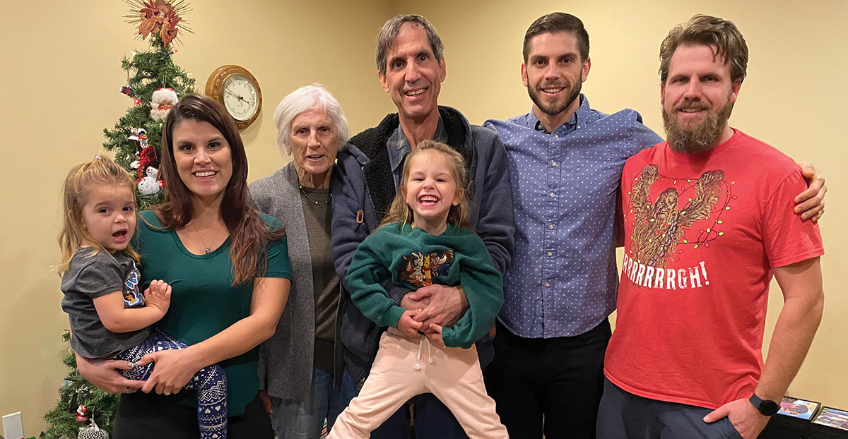 Christopher Taylor and his family poses indoors next to a decorated Christmas tree as a few of these individuals have casual Christmas clothing on