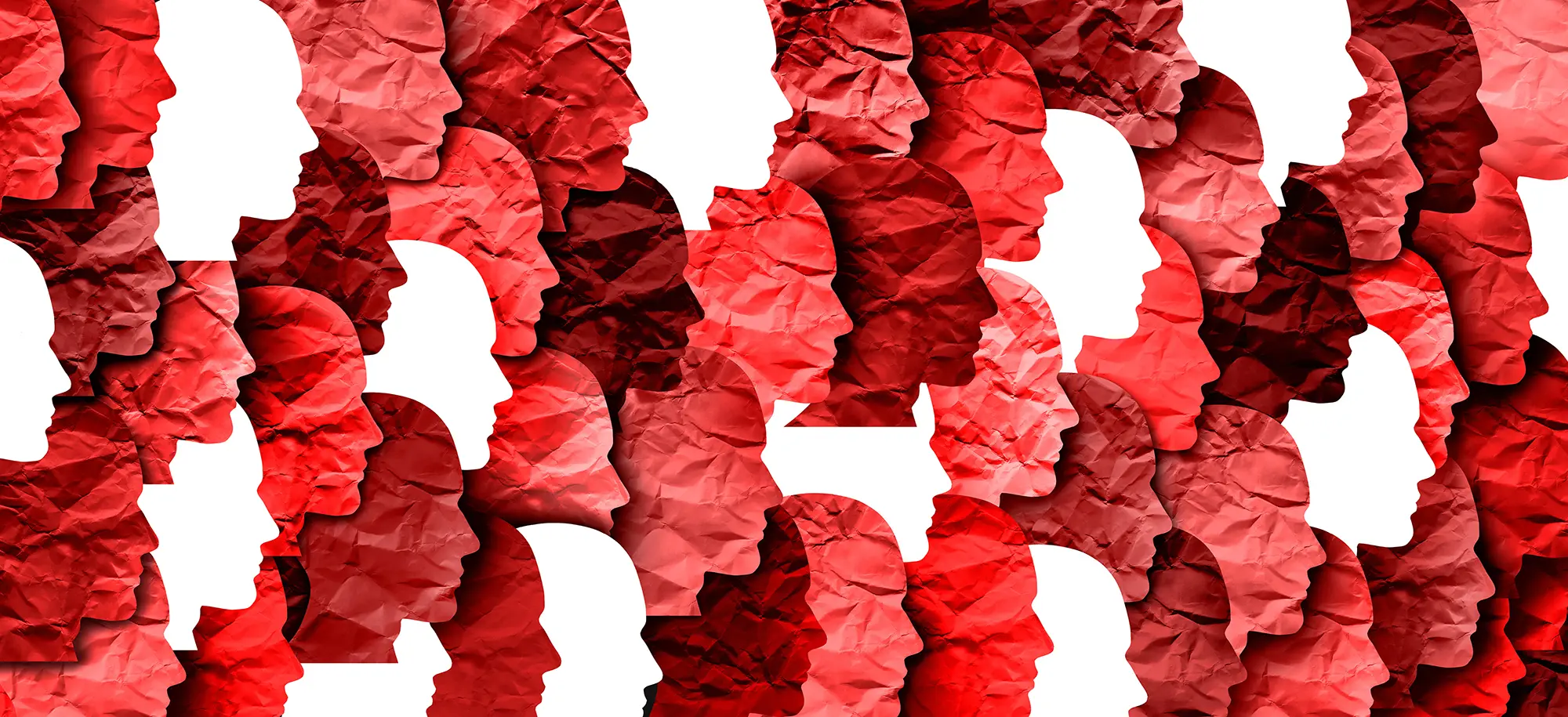 An abstract graphic of overlapping human head profiles facing right. Most of the profiles are textured like crumpled paper in various shades of red, while a few stark white profiles are scattered throughout the group.