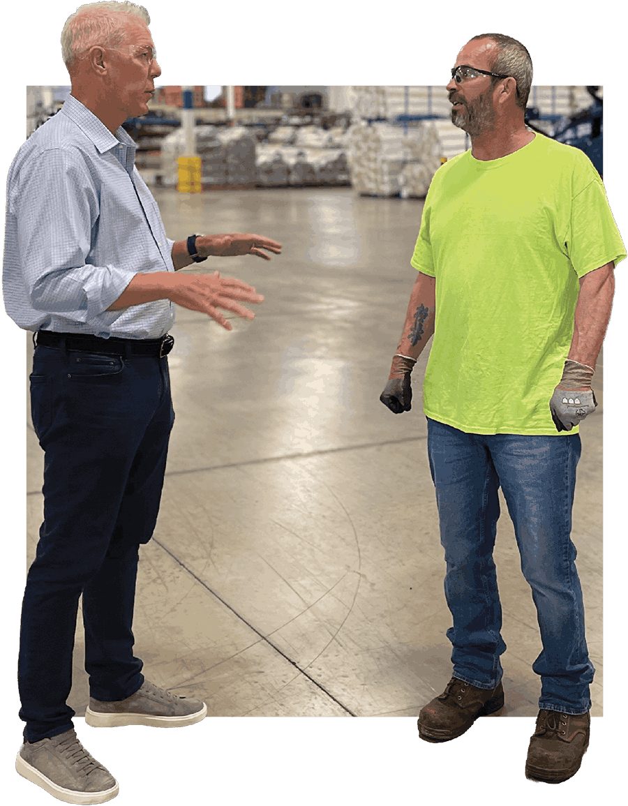 Brad Relford talking to a warehouse employee wearing a bright yellow safety shirt.