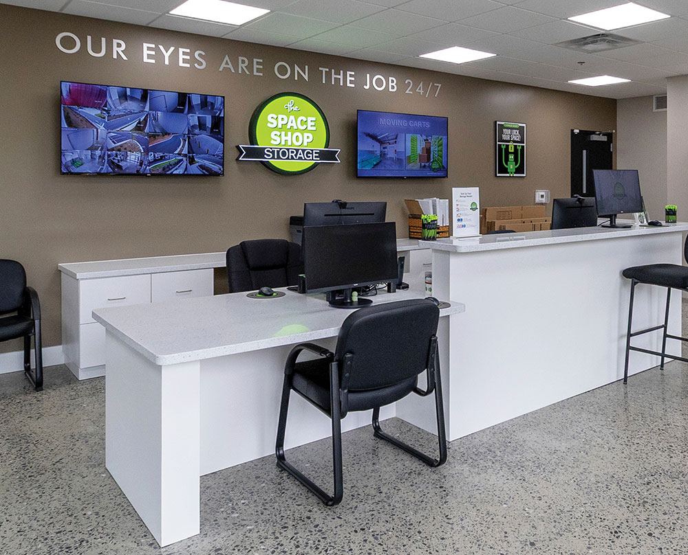 Interior reception area with security monitors and Space Shop Storage signage.