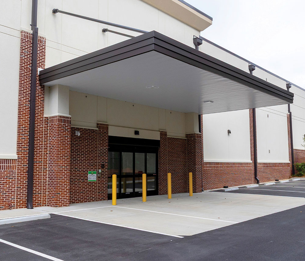 Modern covered drive-through entrance of a brick self-storage facility.