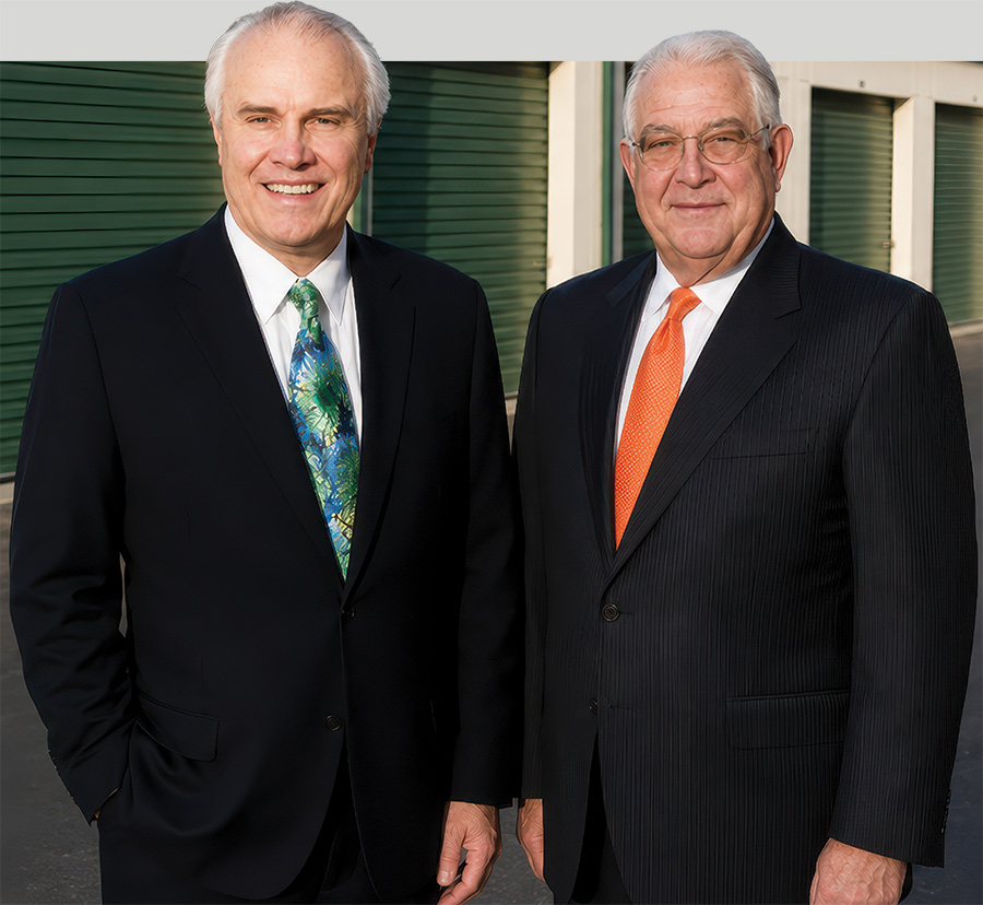 Mike Schofield and Hardy Good in front of green storage units.