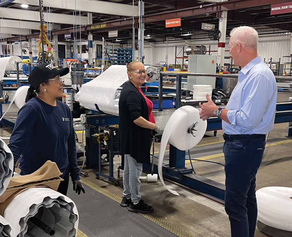 Brad Relford talking to two employees on a factory production floor.
