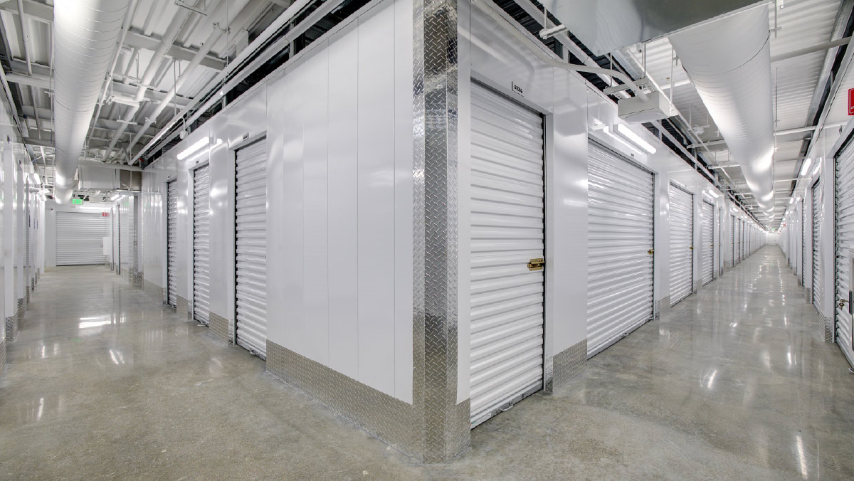 Bright interior hallway of a self-storage facility with white units.