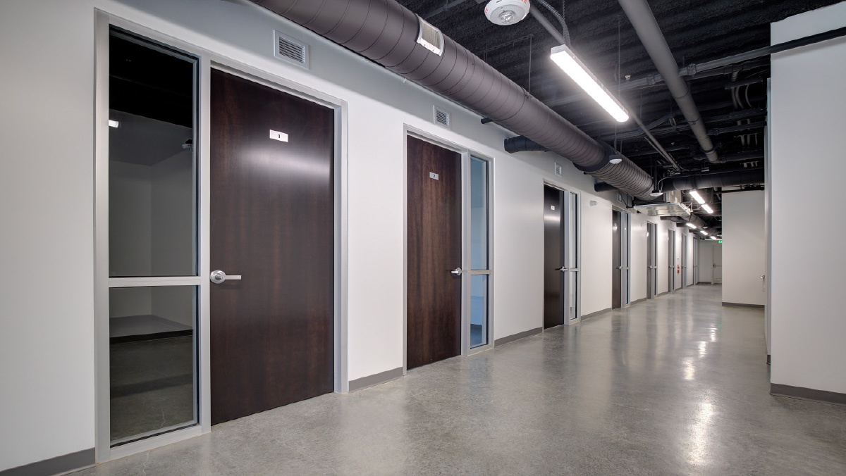 Interior hallway with dark wood-grain doors and polished concrete floors.