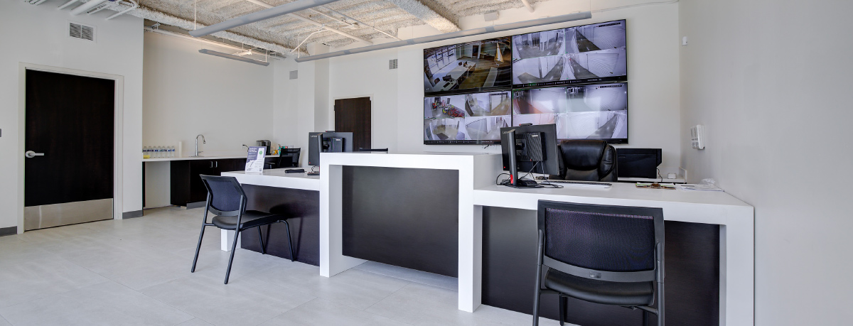 Modern reception office with multiple security monitor screens on the wall.