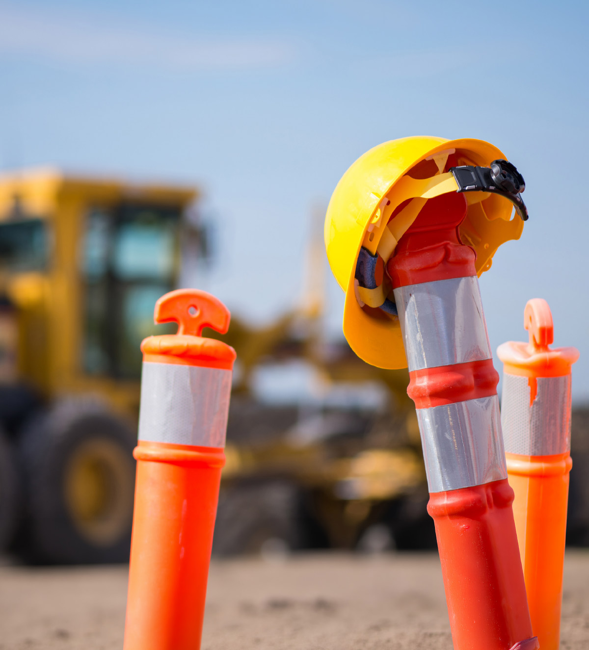 Yellow hard hat on an orange construction bollard at a construction site.
