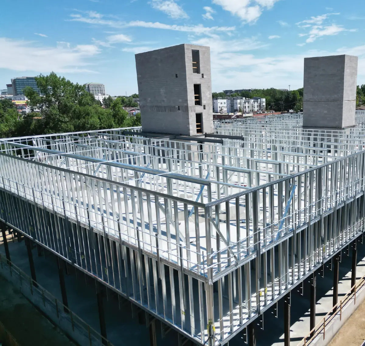 High-angle view of extensive light-gauge steel framing and concrete elevator shafts on a multi-story commercial construction site.