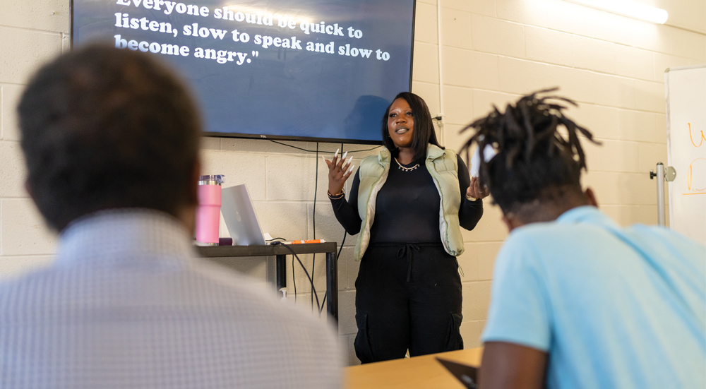 A woman in a vest leads a training session for a group.