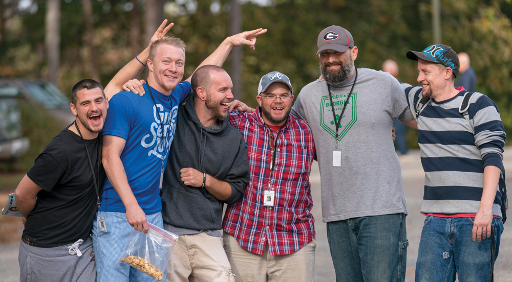 A group of men laughing and embracing in an outdoor setting.