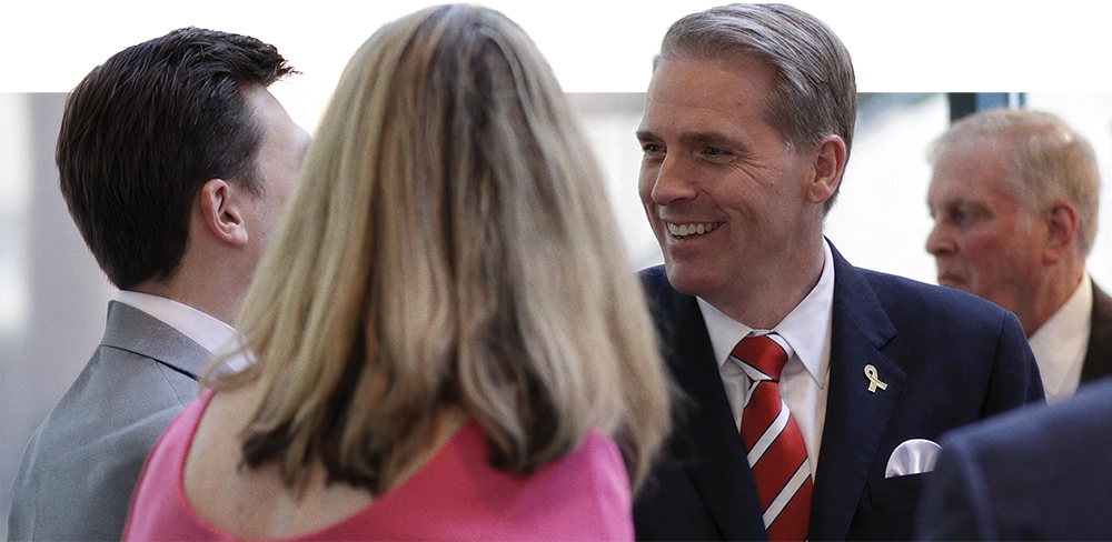 Scott Jennings smiling while talking to colleagues at a professional gathering.