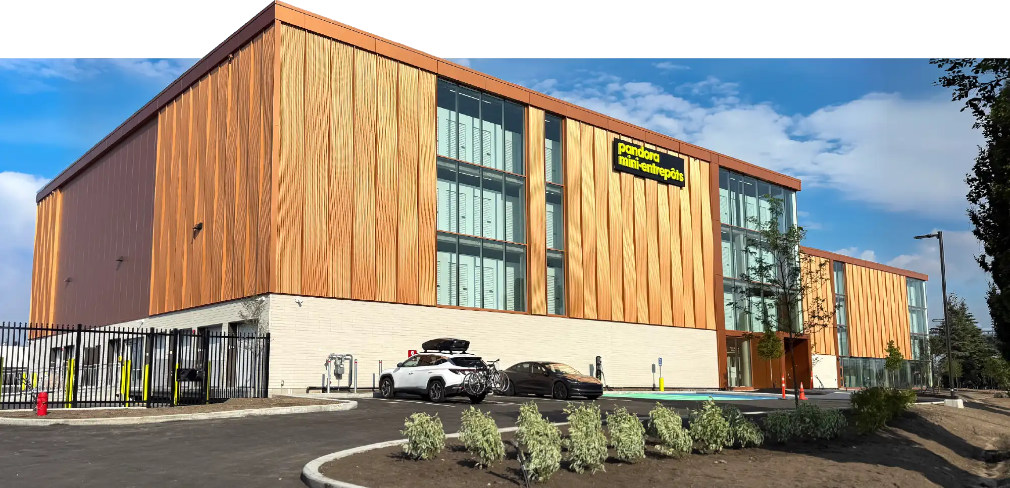Exterior view of a multi-story Pandora Mini-Entrepôts self-storage building with wood-look siding and parking.