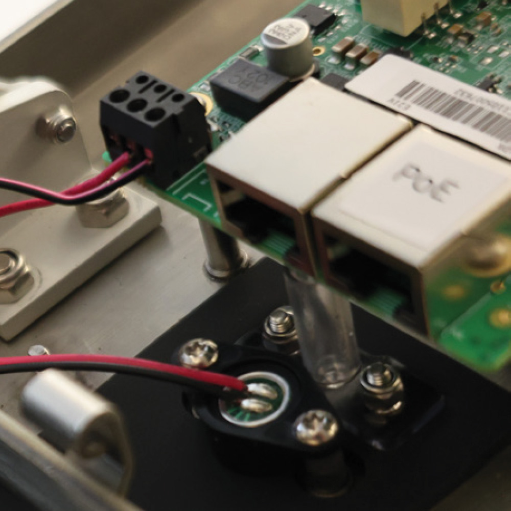 Detailed view of circuit board wiring and PoE Ethernet ports inside an electronic security enclosure.