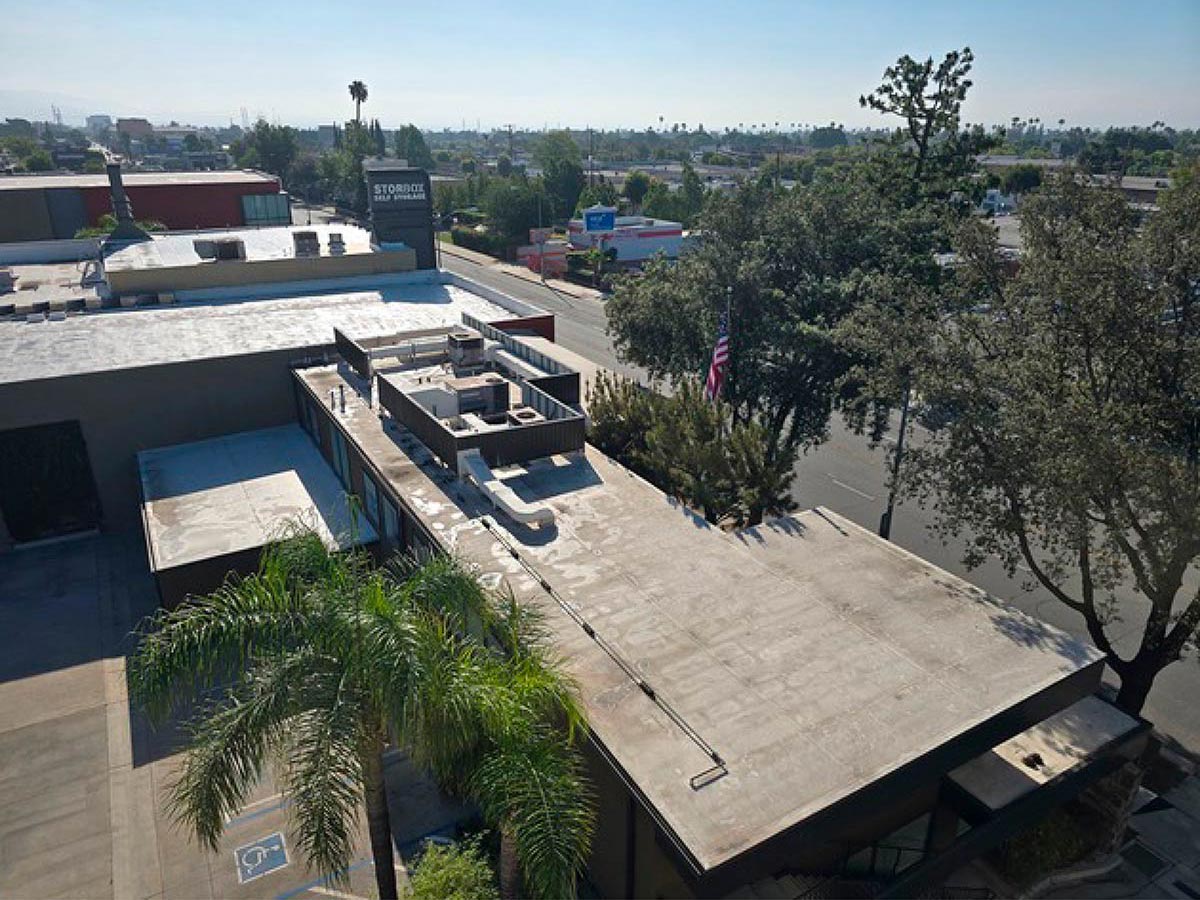 Aerial View Of A Commercial Building With An Aging Flat Roof Showing Wear.