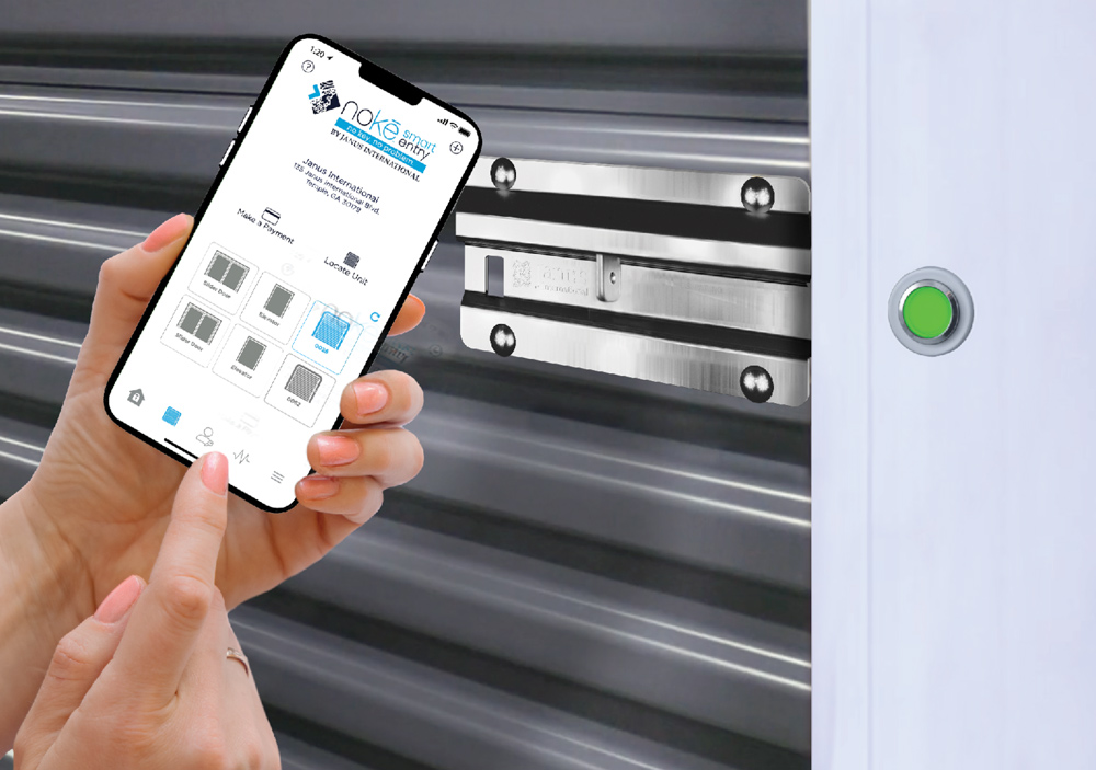 A person holding a smartphone using the Nokē Smart Entry app to unlock a metal storage unit door latch.