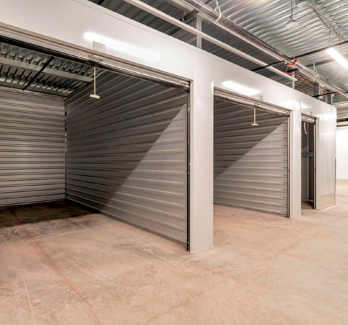 Open metal roll-up doors showing empty indoor climate-controlled storage units.