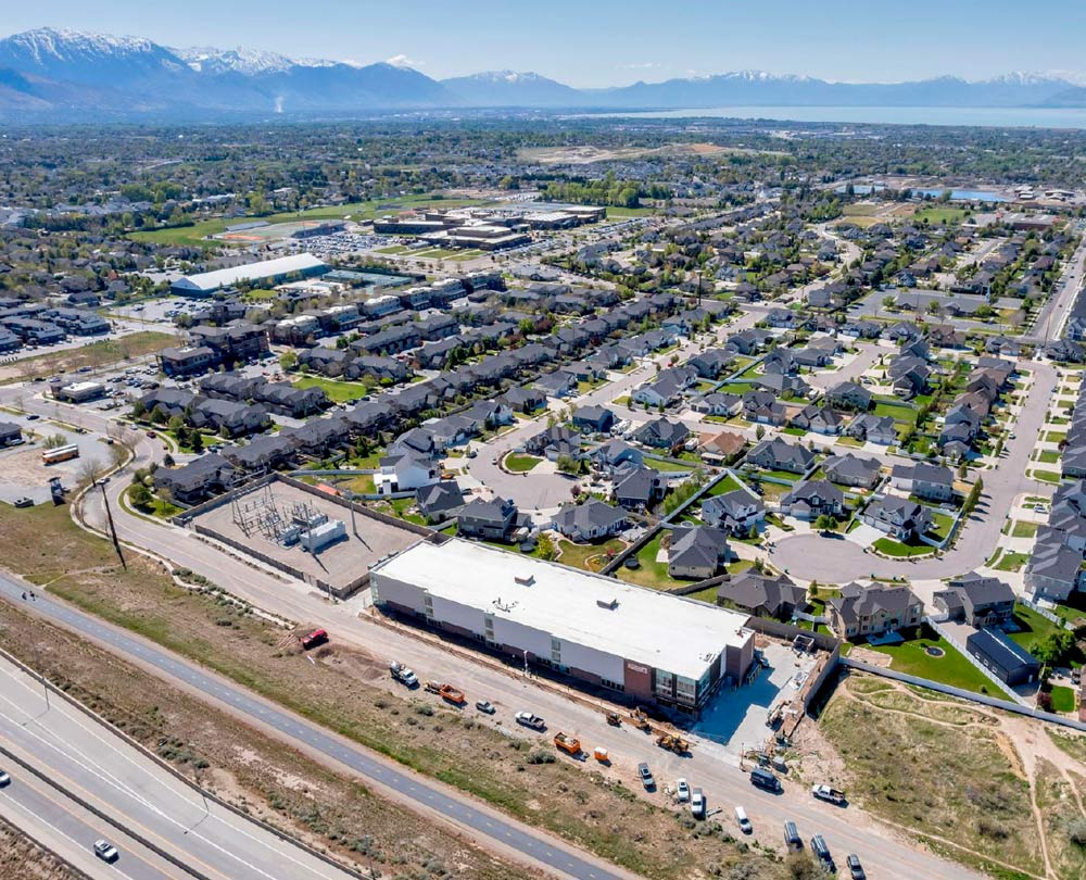 High-angle aerial view of a large self-storage facility adjacent to a residential neighborhood and mountain range.