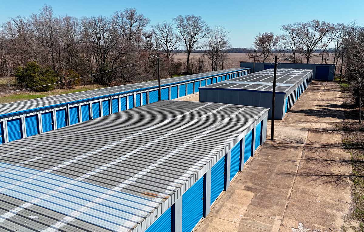 Drone view of self-storage facility rooftops and drive lanes from a distance.