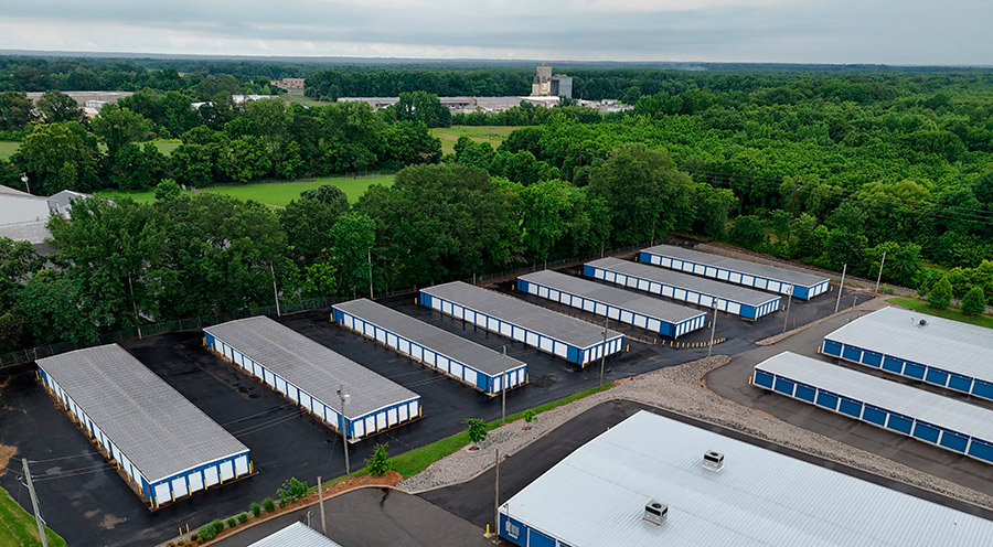 Wide drone perspective of a self-storage facility nestled among lush green trees.