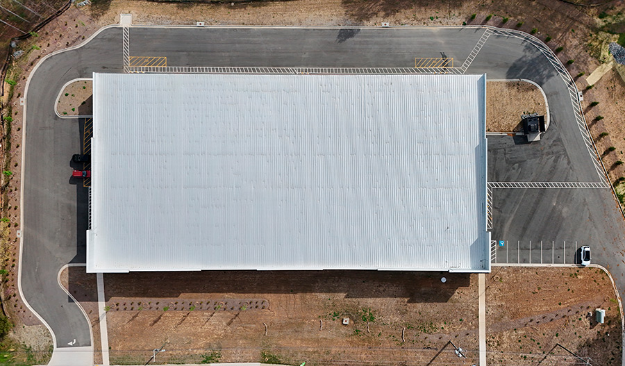 Straight-down aerial view of a large, rectangular self-storage building roof and parking area.