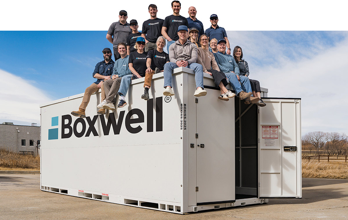 The Boxwell company team sitting on the roof of a branded storage container.