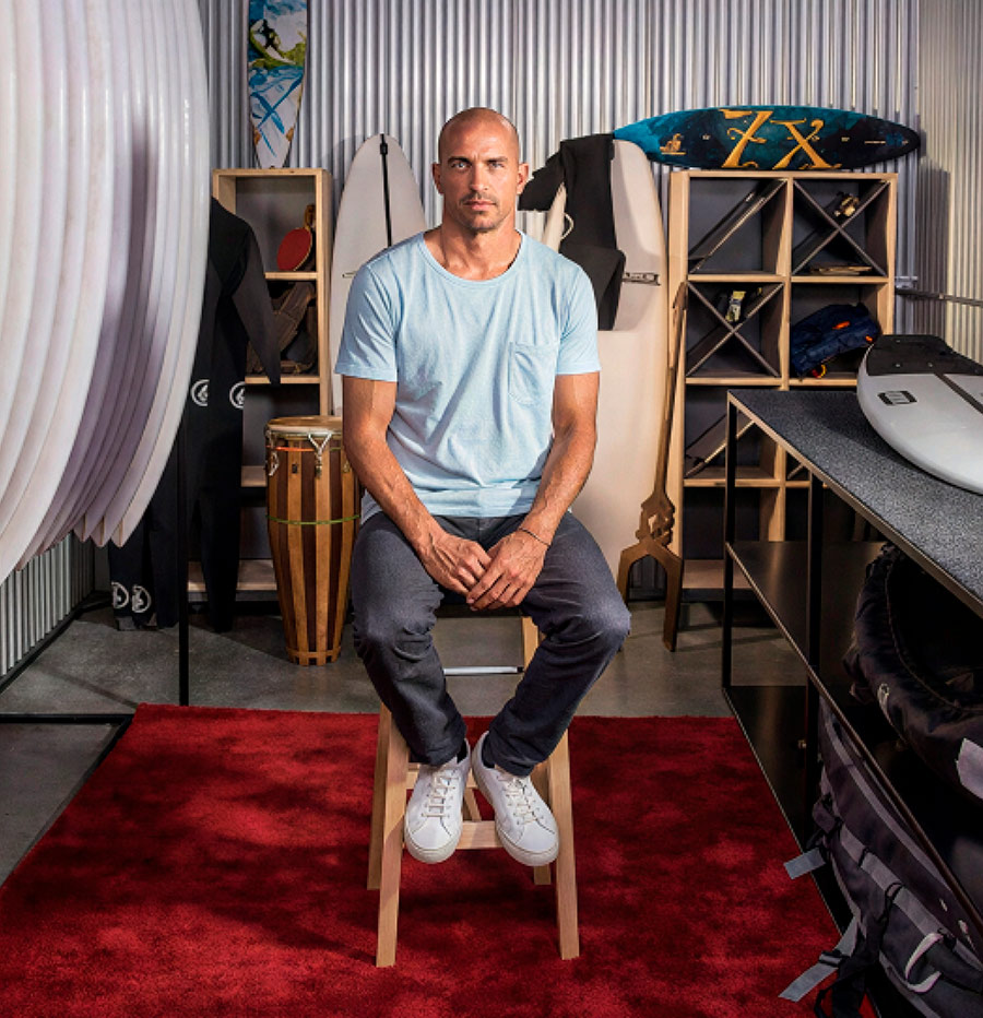 Professional surfer Kelly Slater sitting in his organized storage unit.