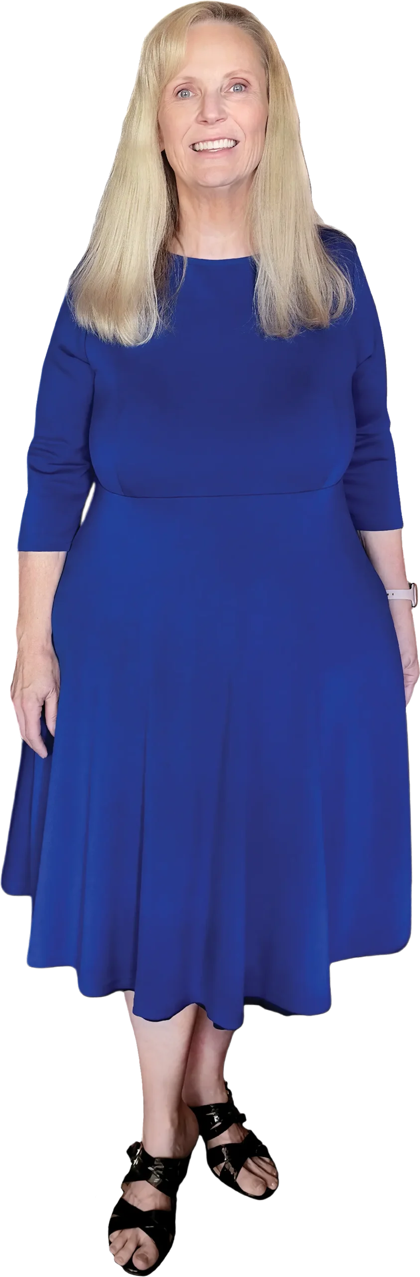 Carol Mixon in a blue dress, smiling with her hands at her sides.